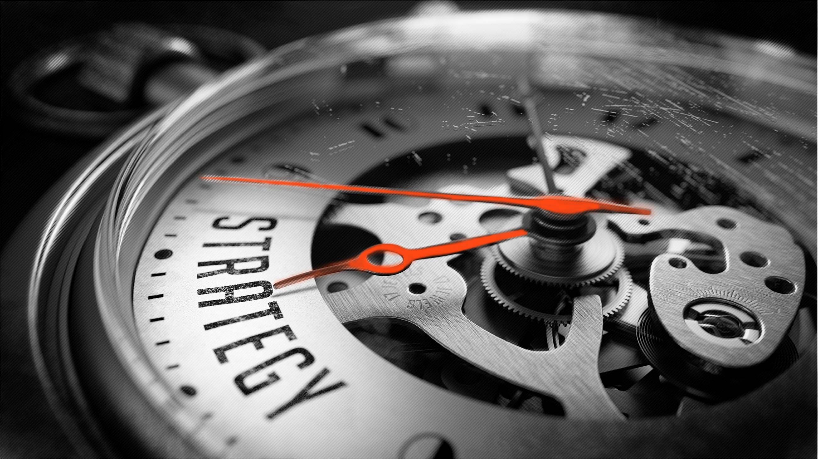 Watch with strategy written on face. The arms are in neon orange, and the image is black and white.